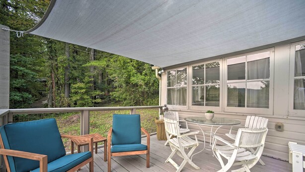 A covered outdoor seating area with wooden furniture and a view of a forested area. - Cozy Stockbridge Cabin - Walk to Beach & Lake! (Stockbridge)