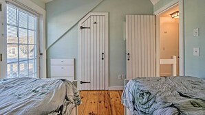 A bedroom with two beds, a white wardrobe, and a bathroom visible through an open door. - Ocean View + Beach Access: Cape Cod Townhome (Mashpee)