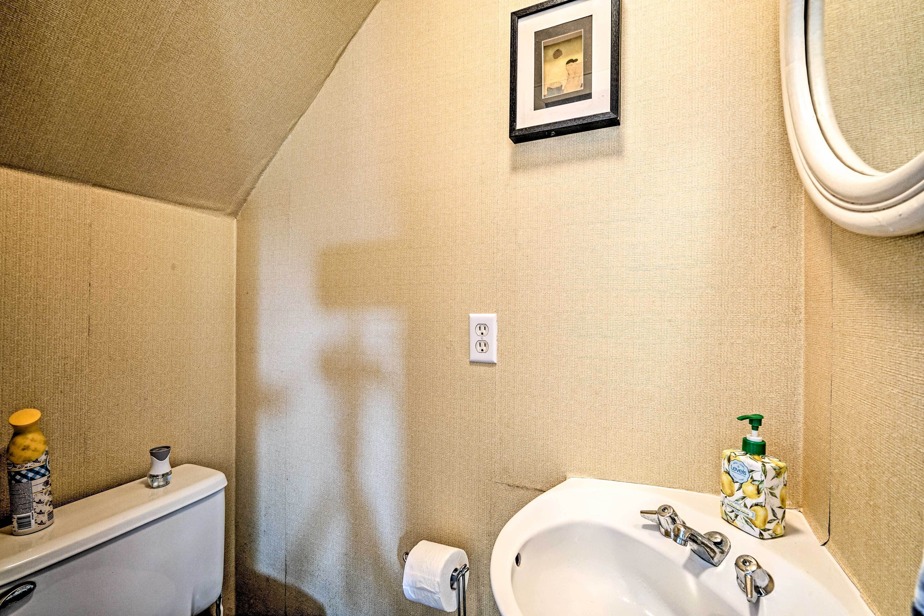 Et badeværelse med toilet, vask og et billede i ramme på væggen.