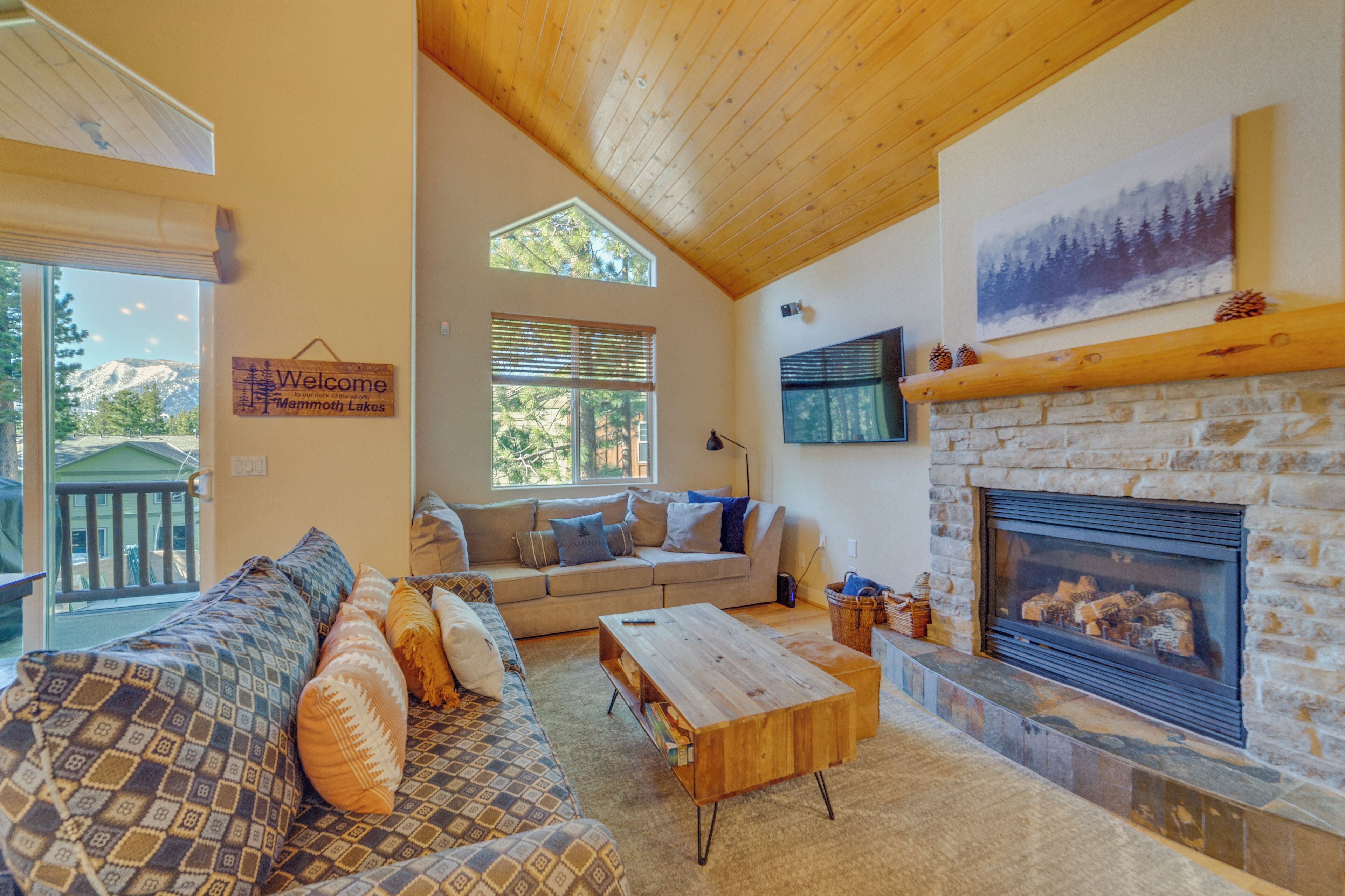 A cozy living room with a stone fireplace, a sofa, and a wooden coffee table.