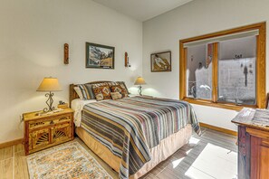 A bedroom with a large bed, two bedside tables with lamps, a wooden nightstand, a patterned rug, and a window with a view. - Comfy 'aspen Ridge' Home ~ 3 Mi to Ski Lifts (Cloudcroft)
