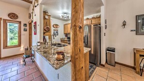 A kitchen with a granite countertop, wooden beams, stainless steel appliances, and a large window. - Comfy 'aspen Ridge' Home ~ 3 Mi to Ski Lifts (Cloudcroft)
