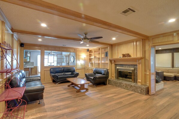 A spacious living room with a fireplace, leather sofas, a coffee table, and a ceiling fan.