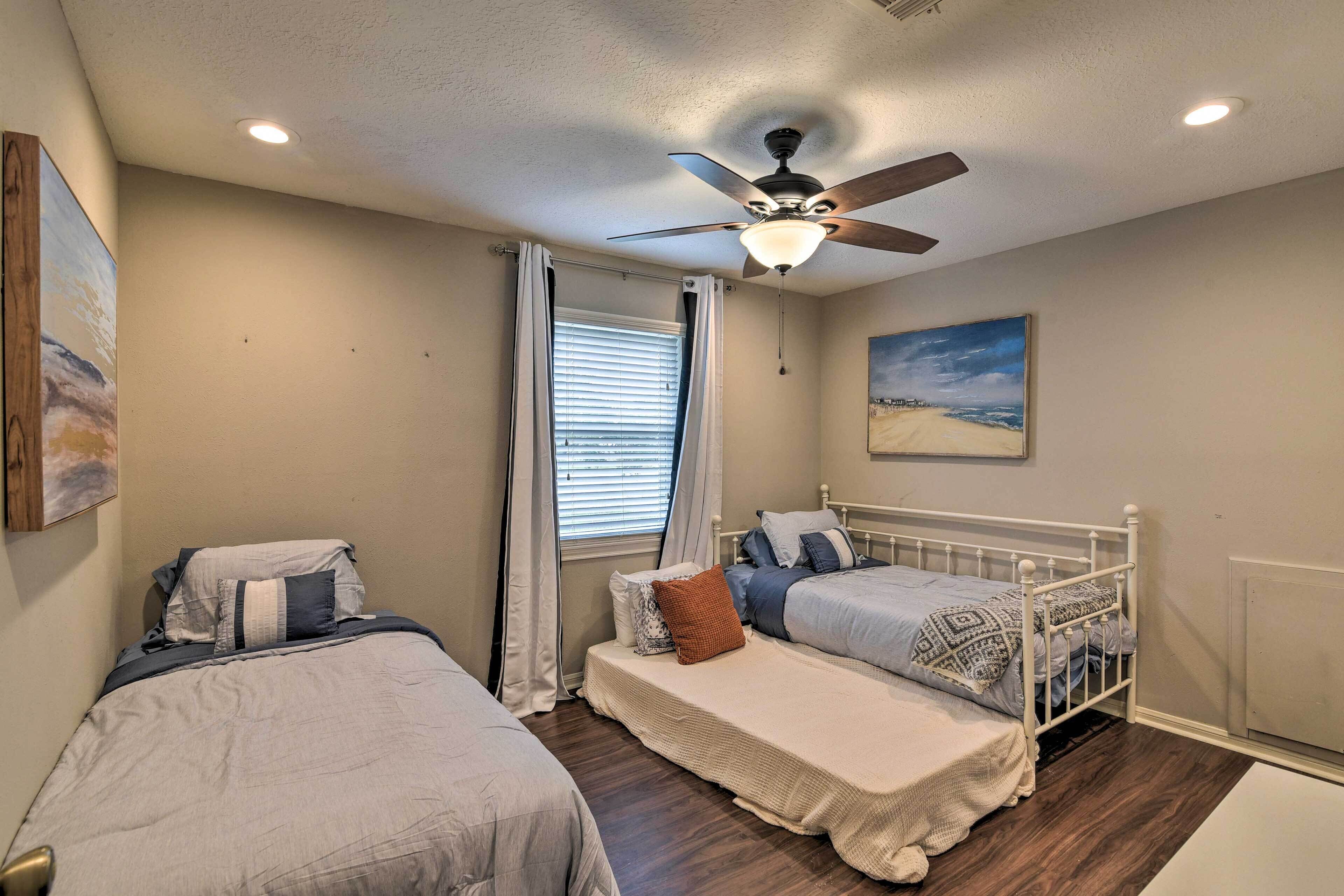 Une chambre avec deux lits, un ventilateur de plafond et une fenêtre avec des rideaux.