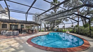 A covered outdoor swimming pool with a wooden deck, surrounded by lounge chairs and a patio area. - Lake Access & Pool: Spacious Freeport Home! (Freeport)