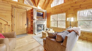 A log cabin interior with a stone fireplace, wooden walls, and a cozy seating area. - Elevated Cabin Bordering Smoky Mountain Nat'l Park (Bryson City)