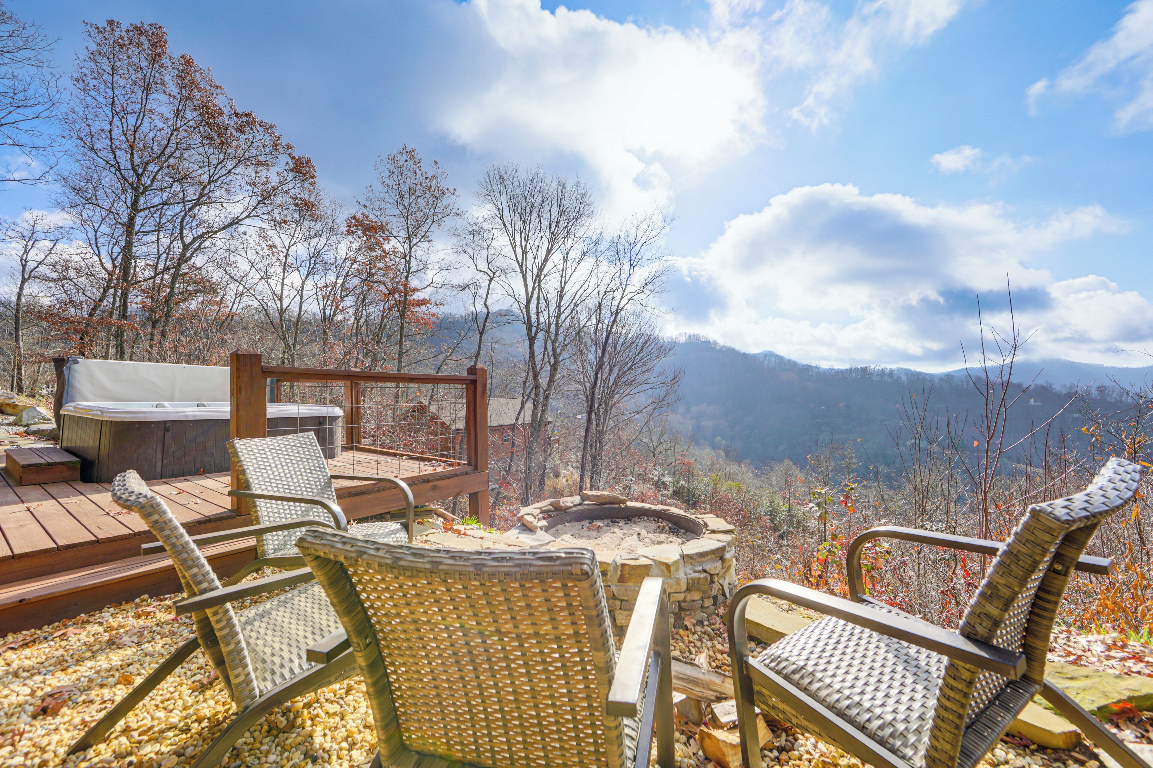 A deck with wicker chairs and a hot tub overlooking a mountainous landscape.