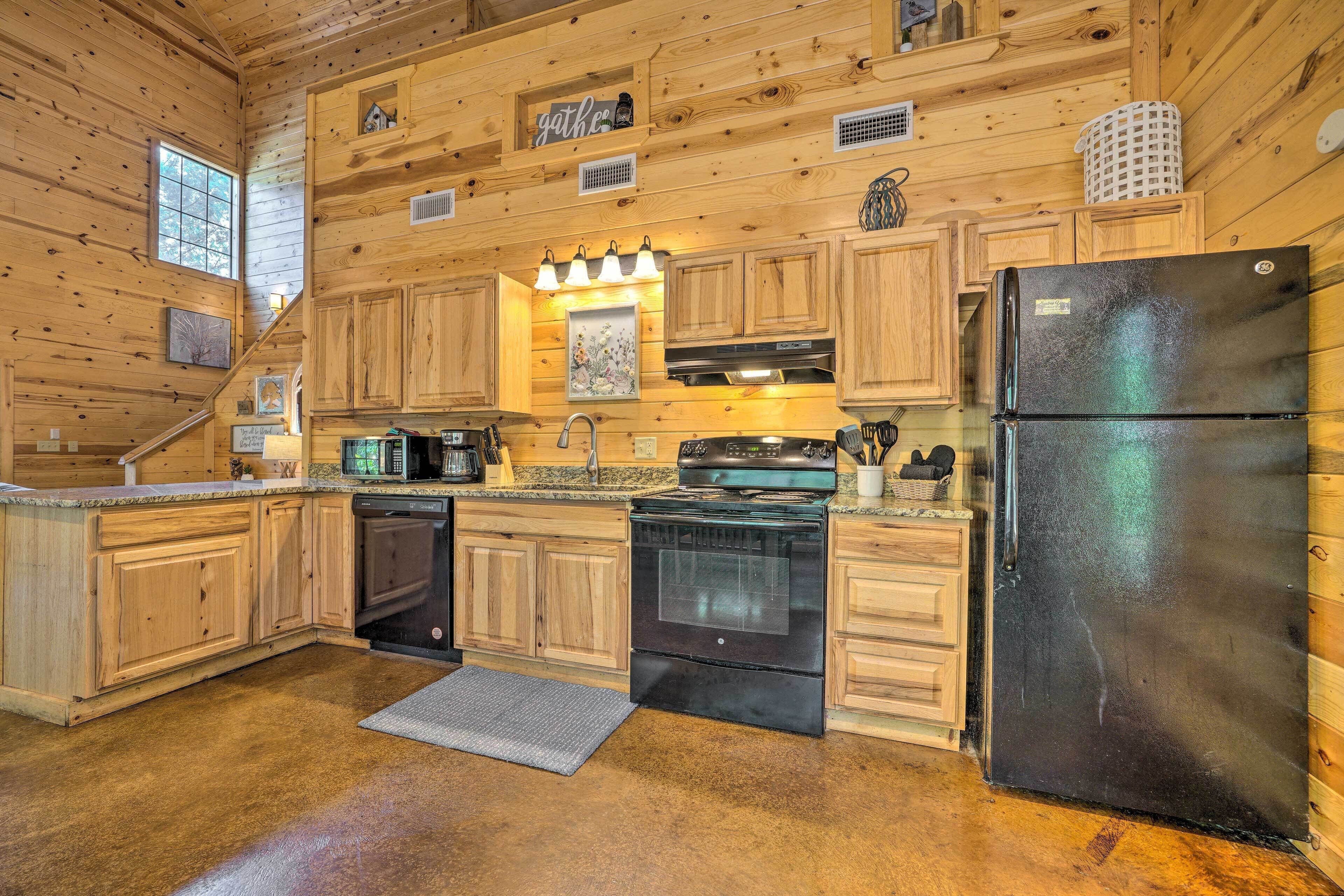 Eine Küchenzeile im Holzblockhausstil mit einem schwarzen Kühlschrank, Edelstahlgeräten und Holzschränken.