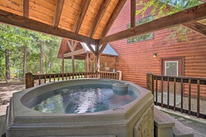 A hot tub in a wooden cabin with a wooden deck and a view of trees.