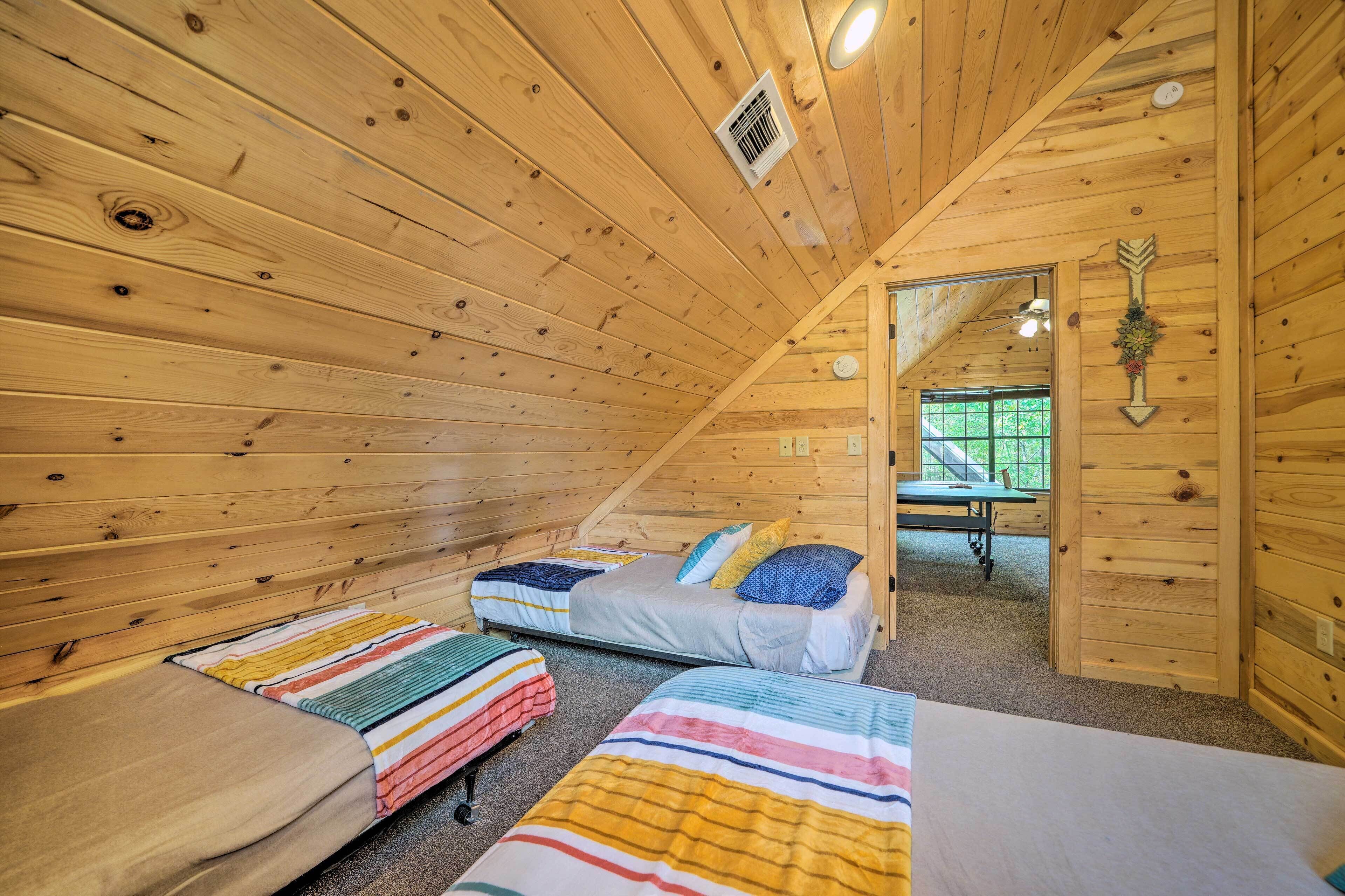 A wooden cabin with two beds, a table, and a window.