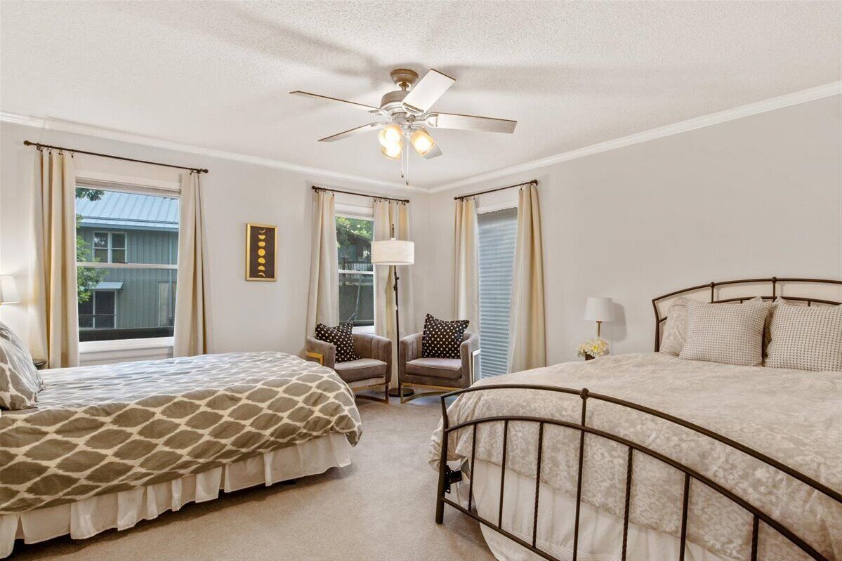 A bedroom with two beds, a ceiling fan, and a view of the outside.