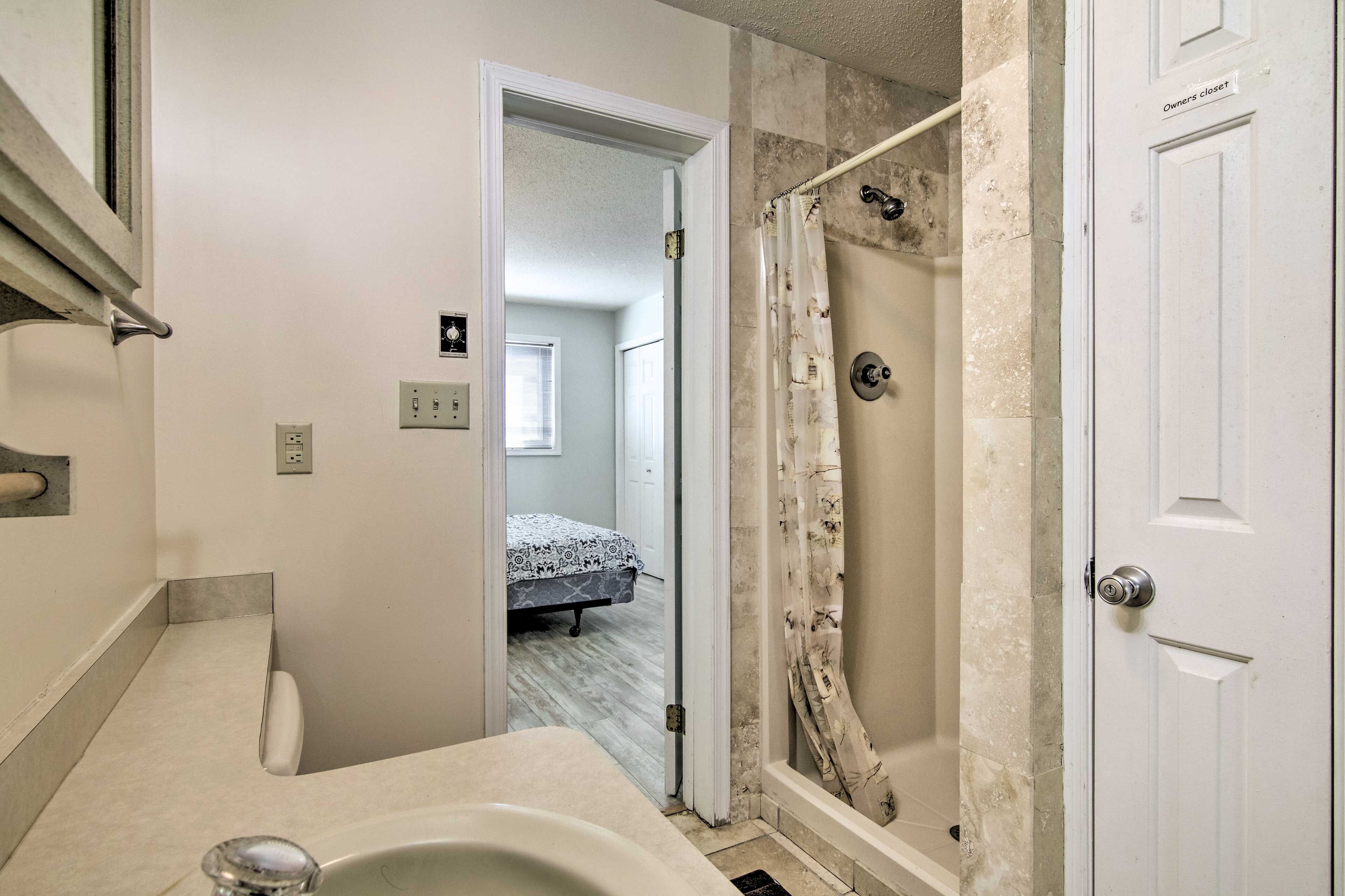 Un baño con bañera, ducha y una puerta que da a un dormitorio.