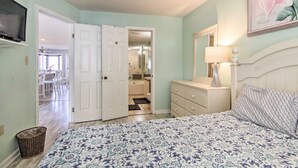 A bedroom with a bed, dresser, and a TV mounted on the wall.