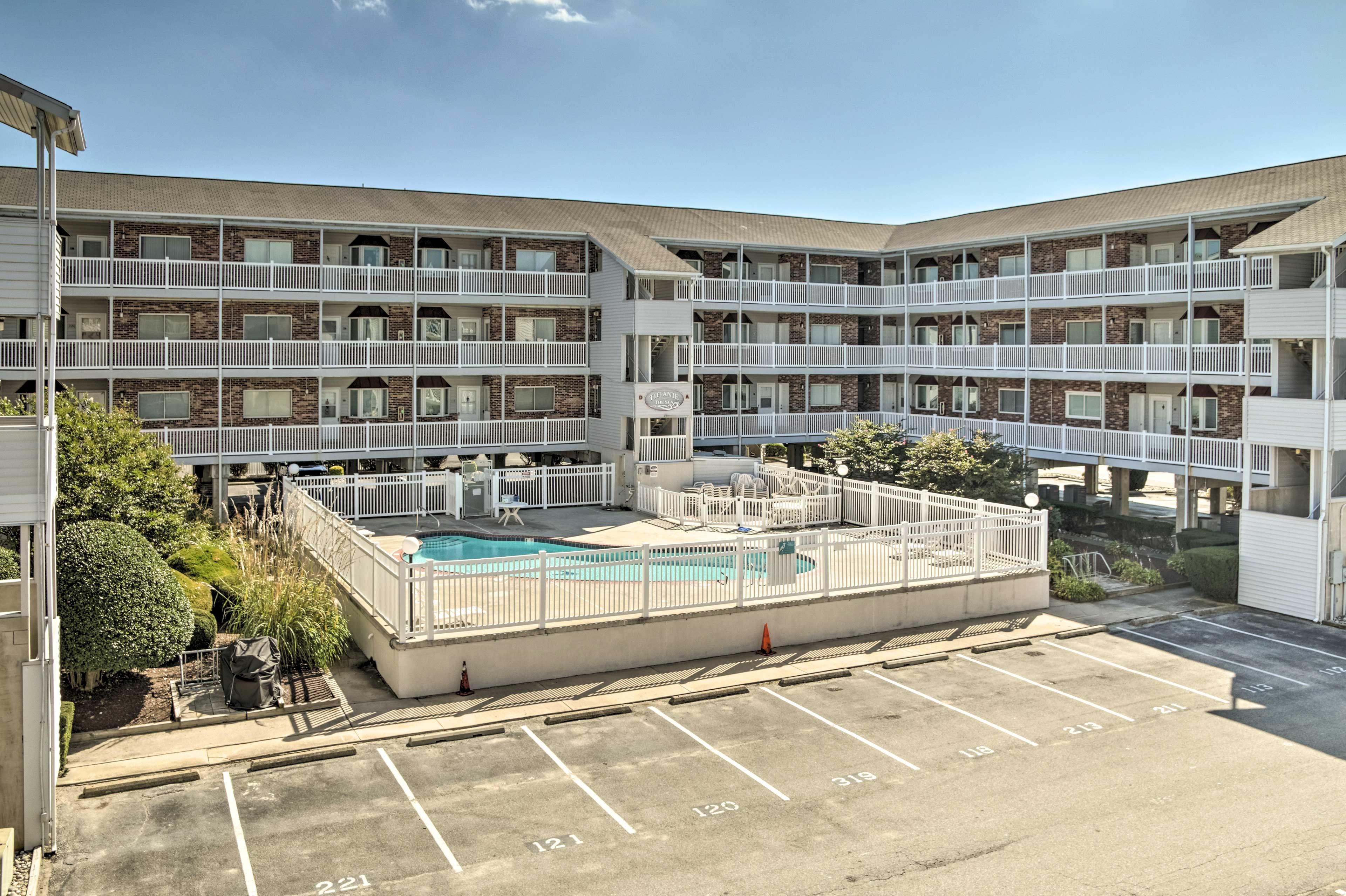A multi-story motel with a rooftop pool and a parking lot.