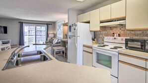 A compact kitchen with a sink, stove, microwave, and refrigerator.
