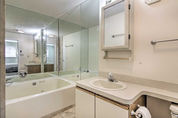 A modern bathroom with a large mirror, a bathtub, and a sink. - Walk to Beach & Dining! Ocean City Condo w/ Pool (Ocean City)