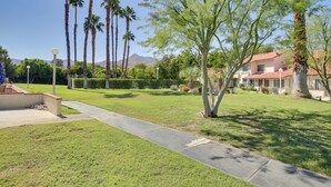 A well-maintained lawn with a pathway, palm trees, and a building with a red roof. - Townhome w/ Pool Access, Near Dtwn Palm Springs! (Palm Springs)