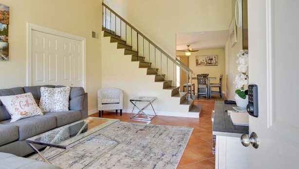 A living room with a sofa, coffee table, and a staircase leading to another room. - Townhome w/ Pool Access, Near Dtwn Palm Springs! (Palm Springs)