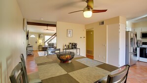 A dining area with a table set for four, a ceiling fan, and a kitchen in the background. - Townhome w/ Pool Access, Near Dtwn Palm Springs! (Palm Springs)