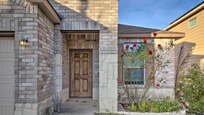 Una casa con fachada de ladrillo, puerta principal de madera y un pequeño jardín con flores.