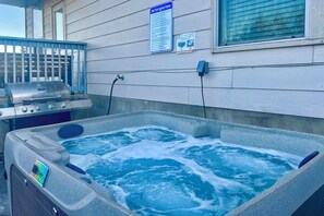 Ein Whirlpool mit Bedienfeld, ein Grill und Sicherheitshinweise an der Wand.