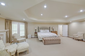 Um quarto espaçoso com uma cama grande, duas poltronas, um banco e uma cadeira.