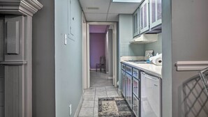 A narrow hallway with a kitchen area on the right, featuring cabinets and a countertop.