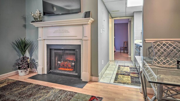 A living room with a fireplace, a television mounted above it, and a dining area with a glass table and chairs.