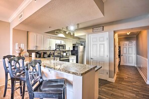 A kitchen with granite countertops, white cabinets, and a central island with bar stools.