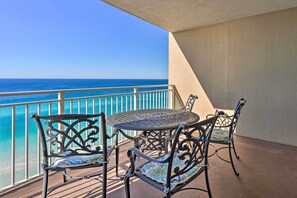 Un balcone con vista sull'oceano, con un tavolo rotondo e quattro sedie con cuscini decorati.