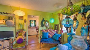 A cozy living room with a wooden cabinet, a blue sofa, and various decorative items including a green hanging lamp and a blue vase. - Walk to Olde Town Arvada - 1940 Vintage Bungalow! (Arvada)