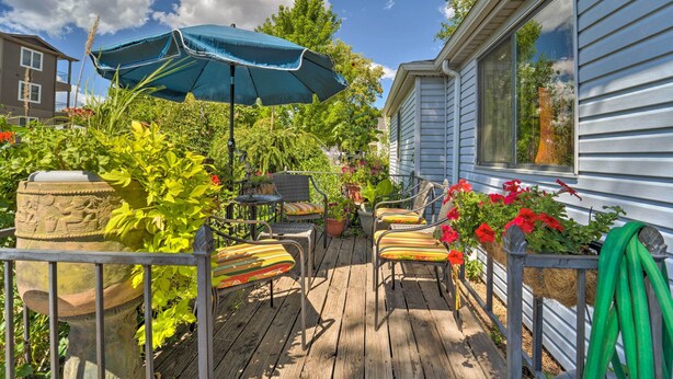 A wooden deck with outdoor furniture, a blue umbrella, and potted plants. - Walk to Olde Town Arvada - 1940 Vintage Bungalow! (Arvada)
