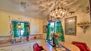 A kitchen with a wooden table, red chairs, a chandelier, and a window with green curtains. - Walk to Olde Town Arvada - 1940 Vintage Bungalow! (Arvada)