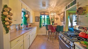 A kitchen with a stove, sink, and chairs. There is a sign that reads "It's Wonderful Life." - Walk to Olde Town Arvada - 1940 Vintage Bungalow! (Arvada)