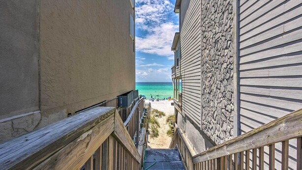 Eine Holztreppe führt zu einem Strand mit einer Steinmauer und Blick auf den Ozean.