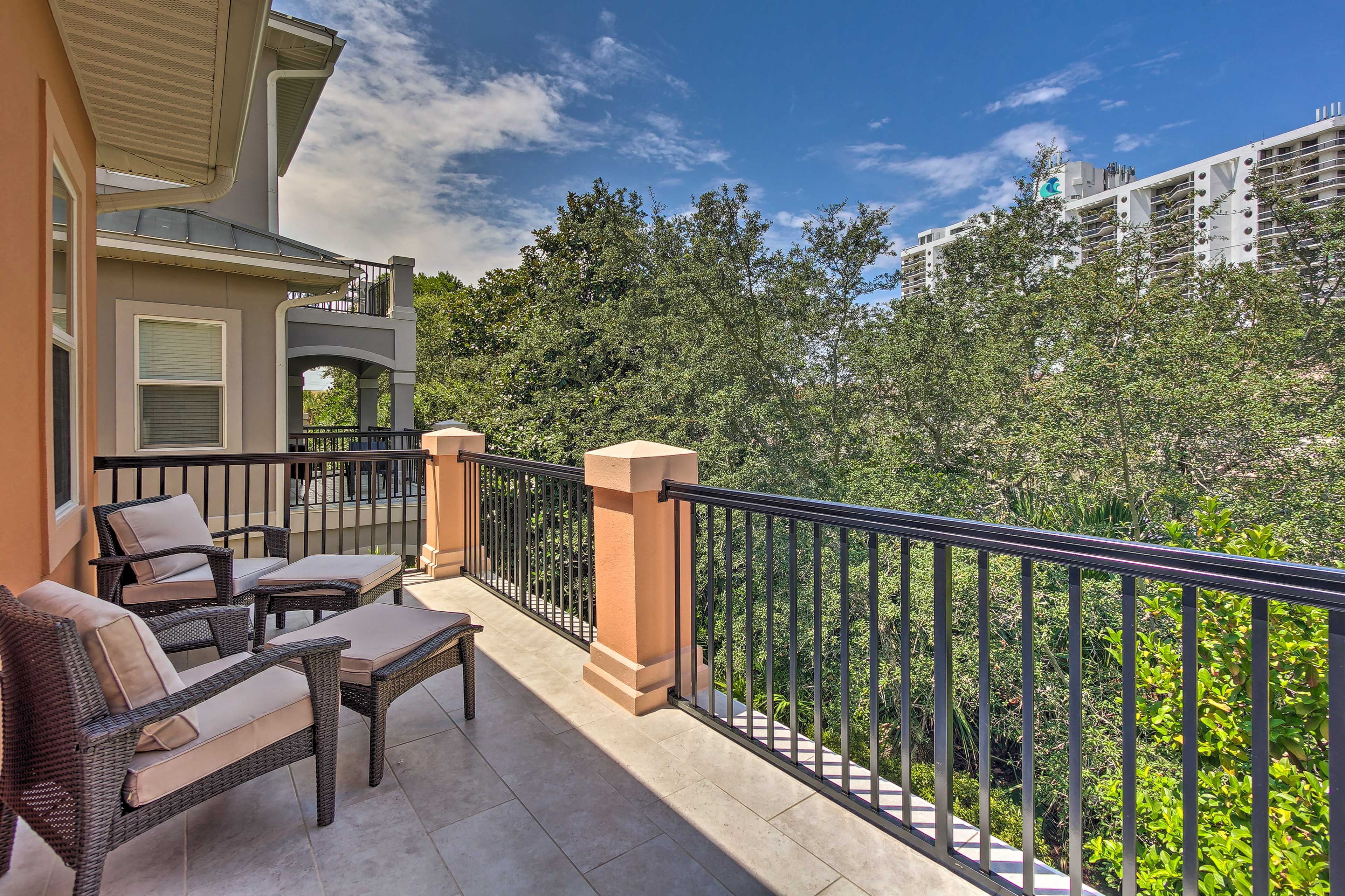 A balcony with wicker furniture and a view of a lush green landscape.