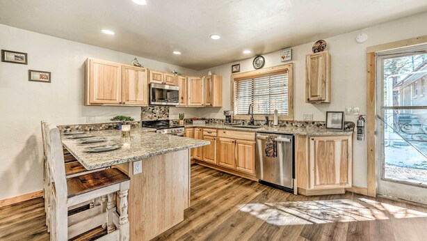 A kitchen with wooden cabinets, granite countertops, and a central island. - Ruidoso Vacation Rental w/ Covered Hot Tub! (Ruidoso)