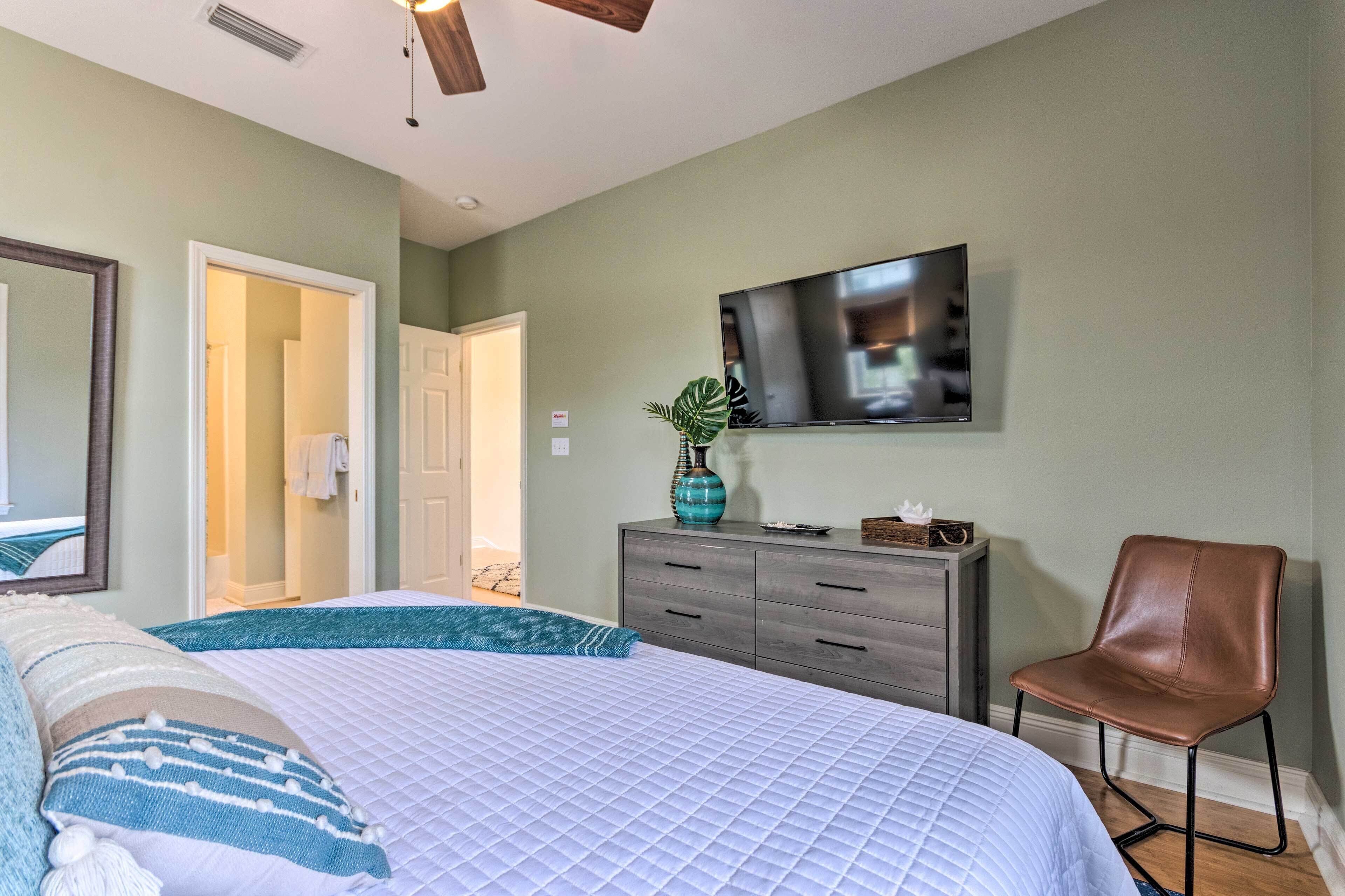 A bedroom with a bed, a dresser, a TV, and a chair.