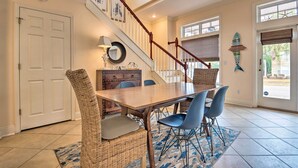 Un coin repas avec une table en bois, des chaises en osier et un escalier doté d’une rampe.