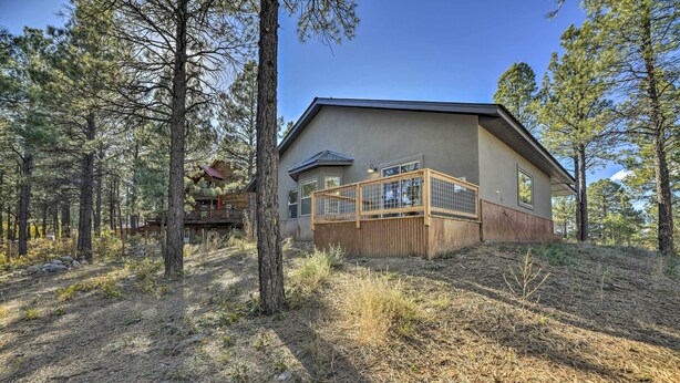 A two-story house with a balcony, surrounded by trees and a dry grassy area.