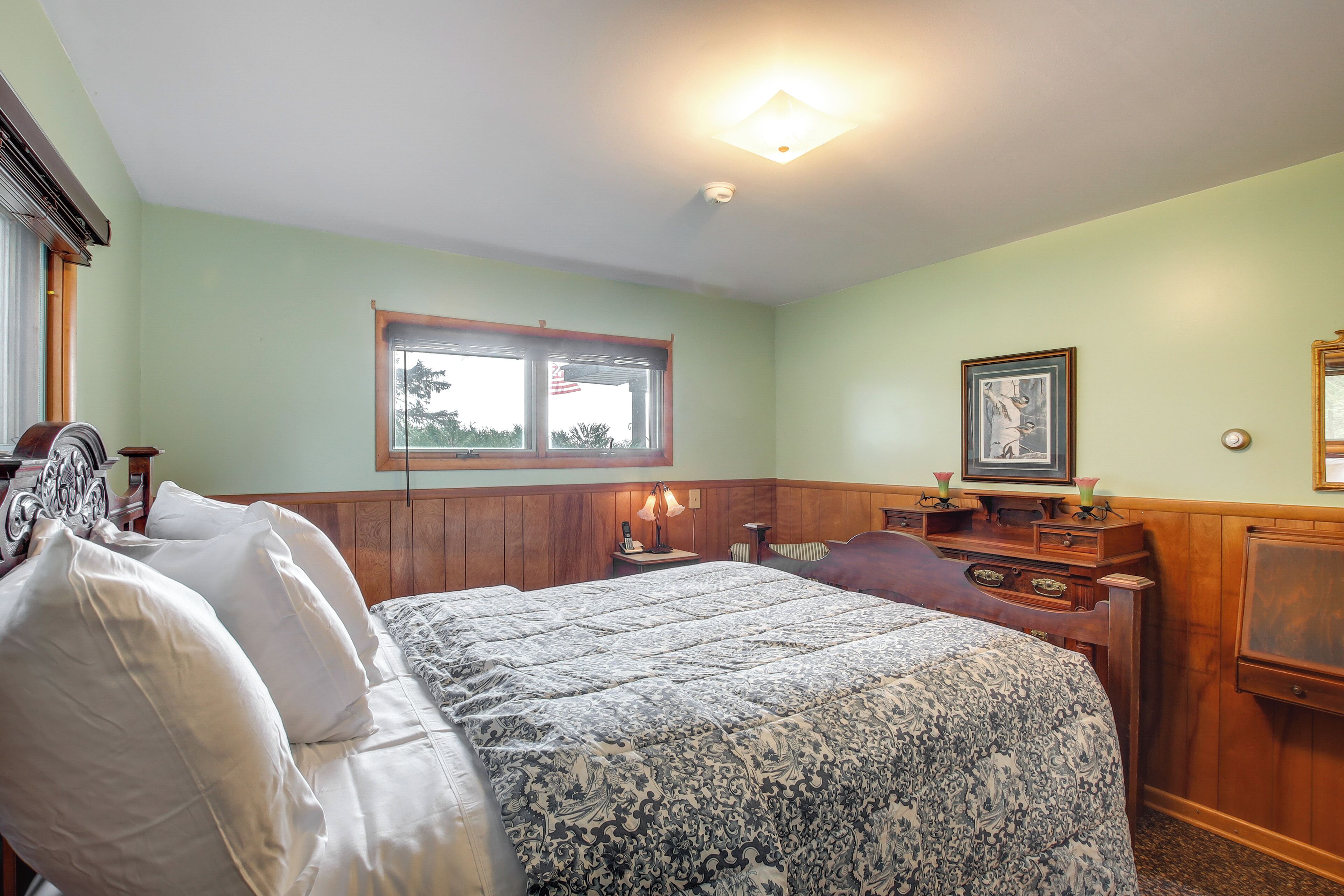 A bedroom with a bed, a nightstand, a dresser, a window, and a ceiling light.