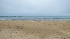 A sandy beach with calm water and a cloudy sky. - Cozy Baileys Harbor Cottage on Lake Michigan! (Baileys Harbor)
