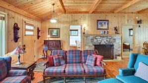 A wooden interior with a plaid sofa, a fireplace, and wooden walls. - Cozy Baileys Harbor Cottage on Lake Michigan! (Baileys Harbor)