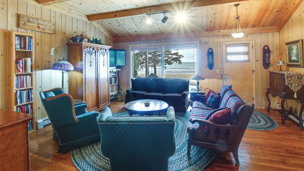 A cozy living room with a fireplace, a television, and a bookshelf. - Cozy Baileys Harbor Cottage on Lake Michigan! (Baileys Harbor)