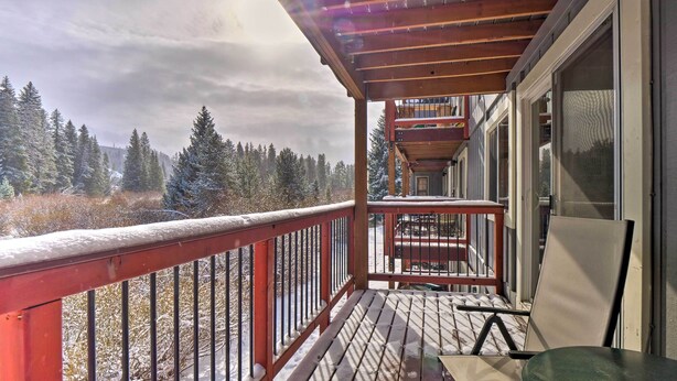 Une terrasse en bois avec une rambarde rouge, une table et une chaise.
