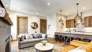 A modern living room with a sofa, a coffee table, and a dining area with stools. - Winter Park Vacation Rental ~ 4 Mi to Slopes (Winter Park)