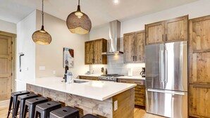 A modern kitchen with wooden cabinets, a stainless steel refrigerator, and a central island with bar stools. - Winter Park Vacation Rental ~ 4 Mi to Slopes (Winter Park)