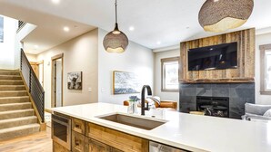 A modern kitchen with a large island, a built-in oven, a dishwasher, and a stone fireplace. - Winter Park Vacation Rental ~ 4 Mi to Slopes (Winter Park)