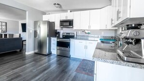 A modern kitchen with white cabinets, stainless steel appliances, and a granite countertop. - Joshua Tree Desert Home (Joshua Tree)