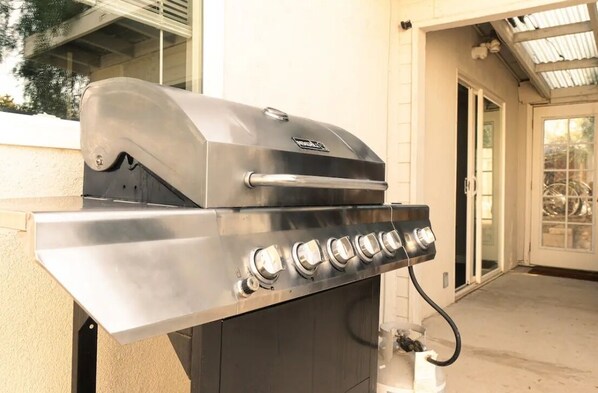 A stainless steel outdoor grill with a control panel, located in a covered patio area with a sliding glass door. - Joshua Tree Desert Home (Joshua Tree)